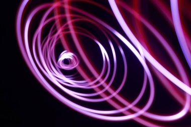 Koyu arkaplanda pembe, kırmızı ve beyaz ışık spiralleri