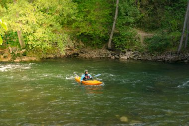 SORT, SPAIN - 26 Temmuz 2021: Nehirde kano çalışması yapan can yeleği ve kasklı bir adam