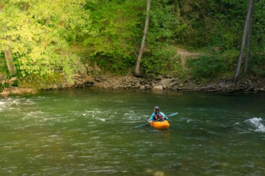 SORT, SPAIN - 26 Temmuz 2021: Nehirde kano çalışması yapan can yeleği ve kasklı bir adam