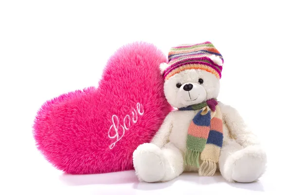 Toy teddy bear sitting with heart-shaped pillow — Stock Photo, Image