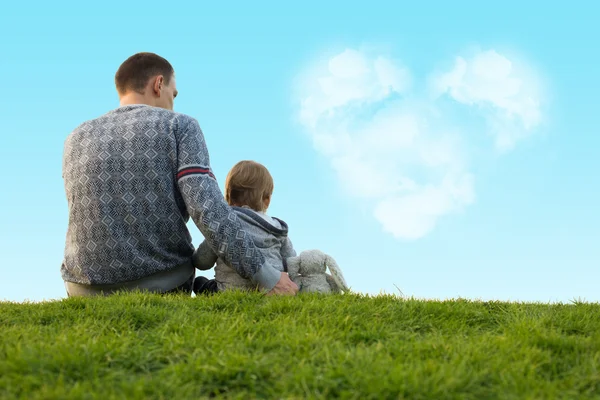 小男孩与他的父亲坐在绿色的草地上 — 图库照片