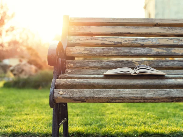Открытая книга, лежащая на скамейке на закате — стоковое фото