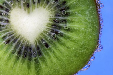 Closeup of a heart shaped kiwi slice covered in water bubbles clipart