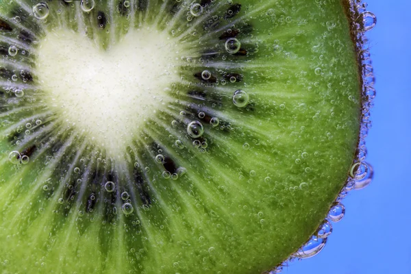 Primer plano de un trozo de kiwi en forma de corazón cubierto de burbujas de agua — Foto de Stock