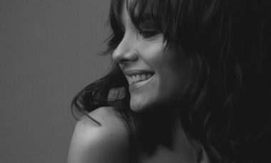 Güzel gülümseyen genç bir kadının siyah beyaz portresi.