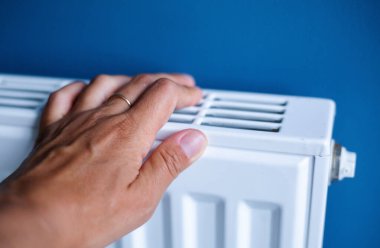 Evdeki ısıtmalı beyaz radyatörün kadın eli. Evde ısıtma mevsiminin sembolik görüntüsü.