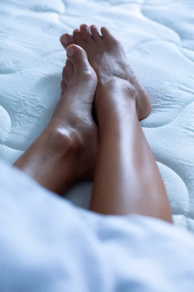 Women\'s feet on a white bed