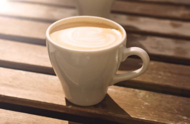 Ahşap bir masada bir bardak kapuçino.