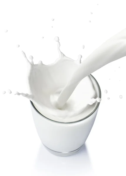 Verter un vaso de leche creando salpicaduras aisladas sobre fondo blanco Imagen De Stock