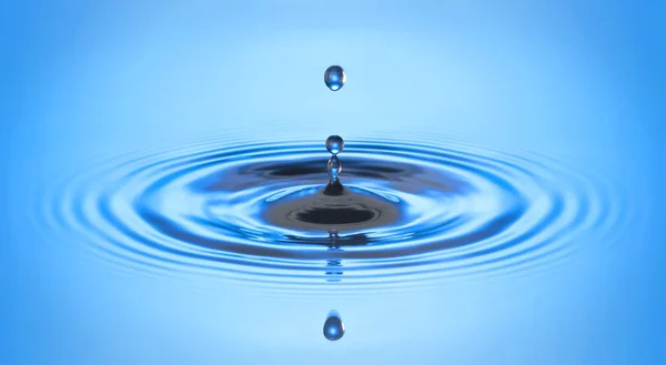 Gota de agua cayendo en el agua haciendo un chapoteo de gotita perfecta y ondulación y ola —  Fotos de Stock