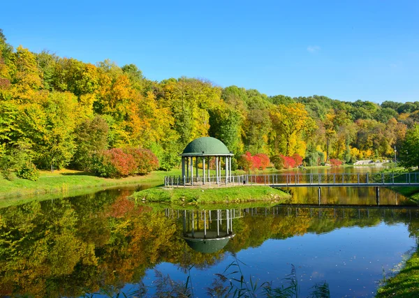 Gazebo and a bridge on a lake in autumn park — Stock Photo, Image