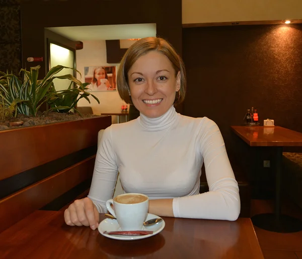 Jovem menina bonita em um café com uma xícara de café . — Fotografia de Stock