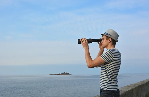 Giovane uomo sta guardando attraverso il cannocchiale al mare — Foto Stock