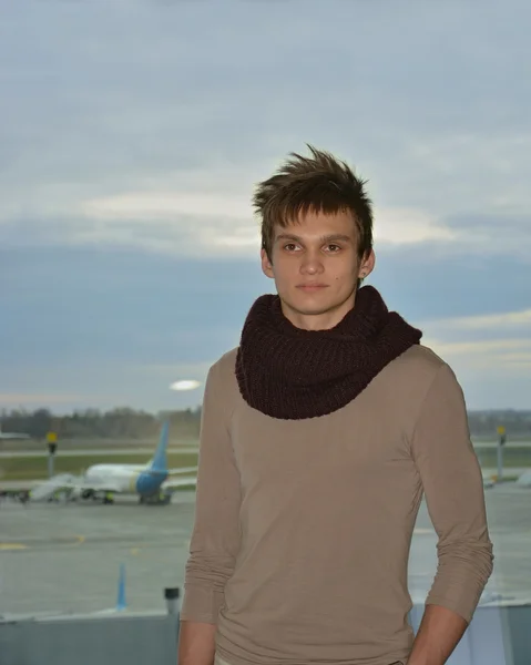 Der junge Mann am Flughafen vor dem Hintergrund von Flugzeugen — Stockfoto
