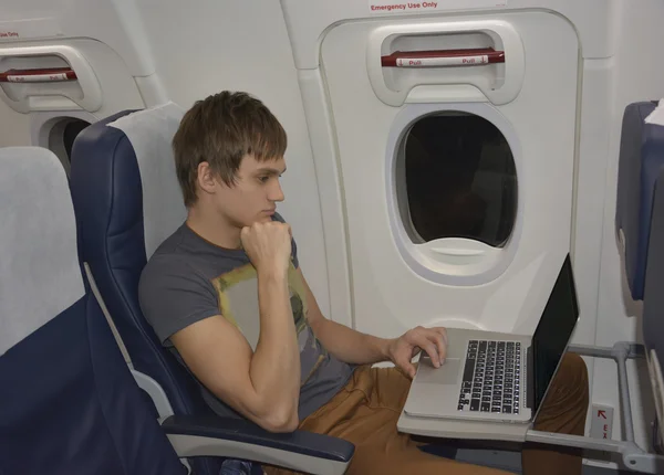 Bir dizüstü bilgisayar ile Uçaktaki adam — Stok fotoğraf