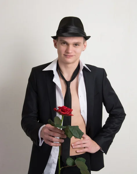 Ein junger Mann mit Hut und Krawatte mit einer Rose. — Stockfoto