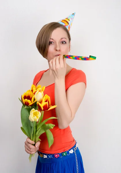 Woman celebrating birthday with tulips and party hat — Stock Photo, Image