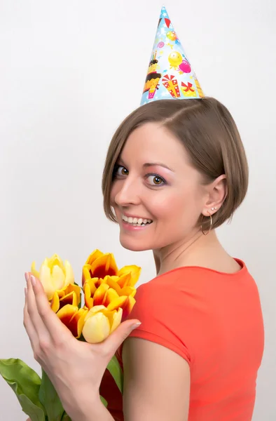 Mujer celebrando cumpleaños con tulipanes y sombrero de fiesta —  Fotos de Stock