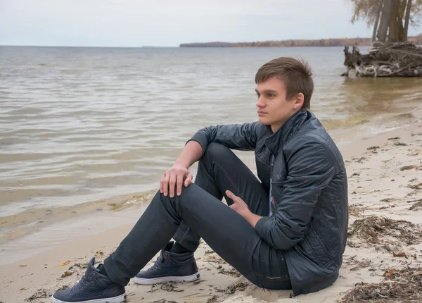 The guy who is sitting on the shore of the sea of autumn — Stock Photo, Image