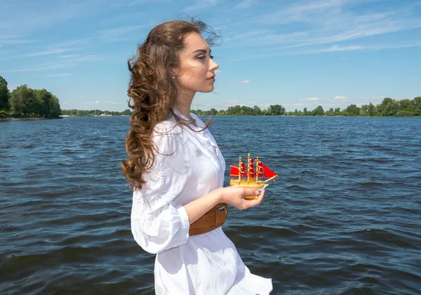 A rapariga tem um pequeno navio com velas vermelhas. Assol moderno . — Fotografia de Stock