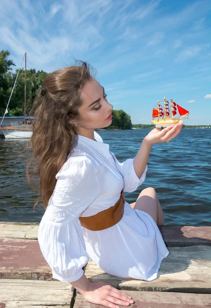 Chica sostiene un pequeño barco con velas rojas. Assol moderno . —  Fotos de Stock