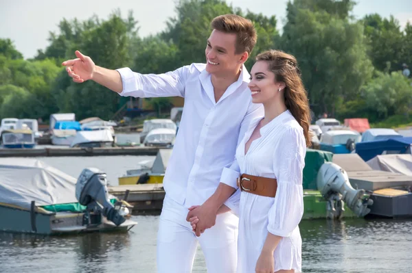 Jongen houdt het meisje de hand op een pier in de buurt van het water. — Stockfoto