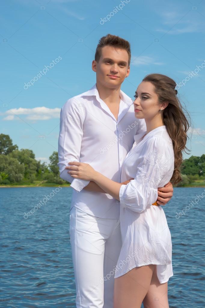 Guy hugs a girl near the water. Couple in love.