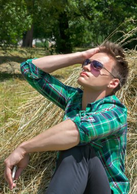 haystacks içinde otururken bir cep telefonu ile genç adam