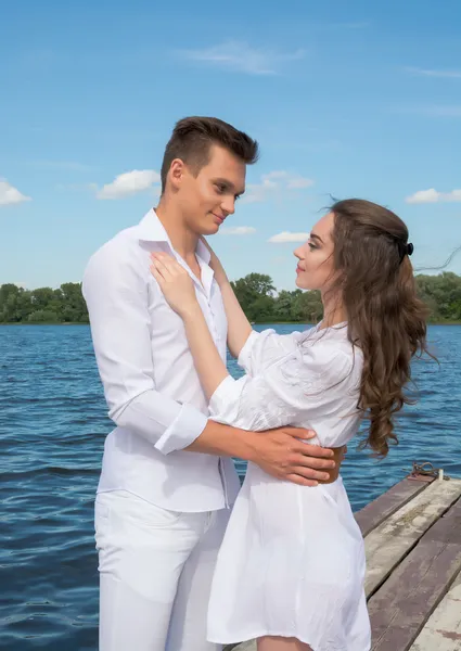 Guy hugs een meisje in de buurt van het water. — Stockfoto