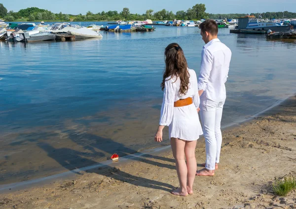 Homem e mulher em pé na margem do rio e ver fora do barco de brinquedo wi — Fotografia de Stock