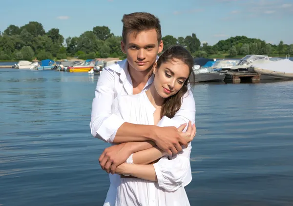 Uomo abbracciare donna vicino a un'acqua di fronte alle barche — Foto Stock