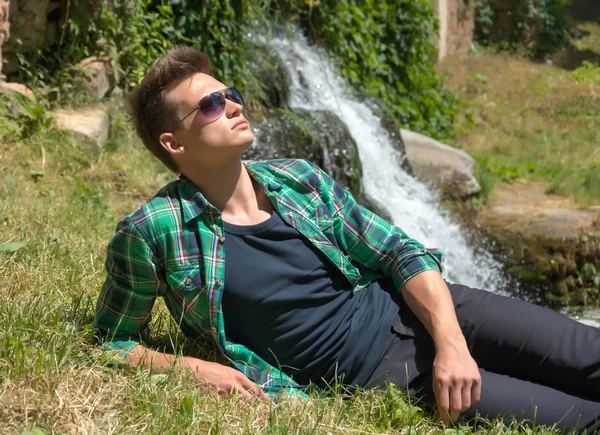 Guy aux lunettes de soleil relaxant dans la nature près de la cascade — Photo