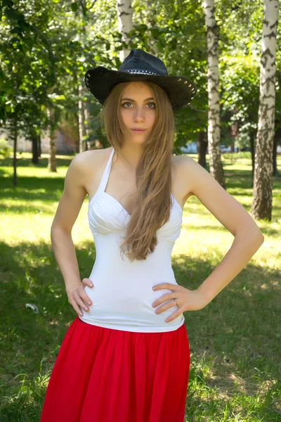 Chica en un sombrero de vaquero y una falda roja en el parque de verano —  Fotos de Stock