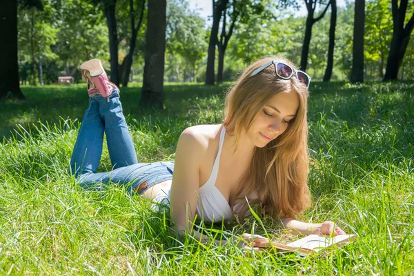 Chica en gafas de sol leyendo un libro en un parque de verano —  Fotos de Stock