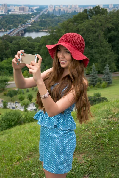 Beautiful woman in a red hat taken picture of herself, selfie. — Stock Photo, Image