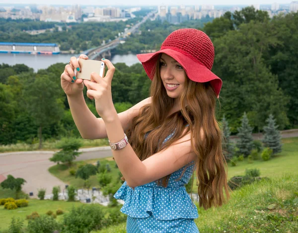 Belle femme dans un chapeau rouge pris en photo d'elle-même, selfie . — Photo