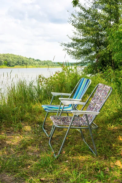 Twee vouwen stoelen op de natuur, aan de oevers van de rivier — Stockfoto