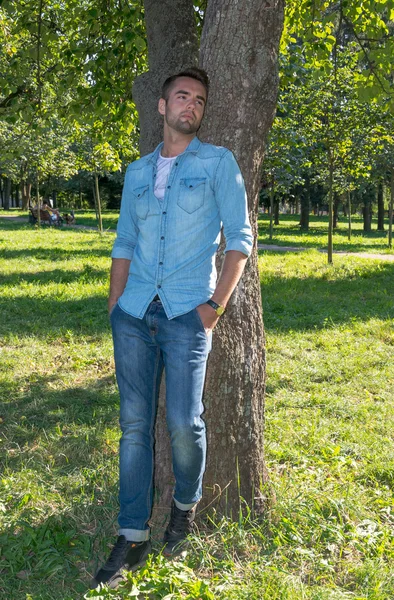 Jeune homme debout à l'arbre dans le parc en été — Photo