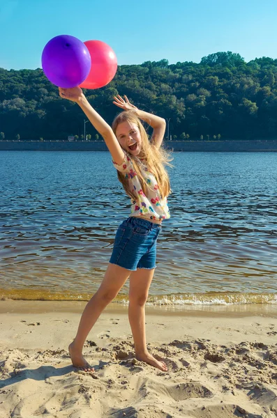 Щаслива дівчина з різнокольоровими кульками на пляжі — стокове фото