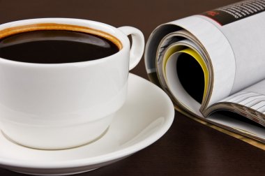 bir fincan kahve ve açılan dergisi