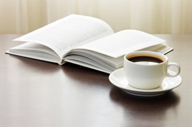 bir fincan kahve ve açılan kitap