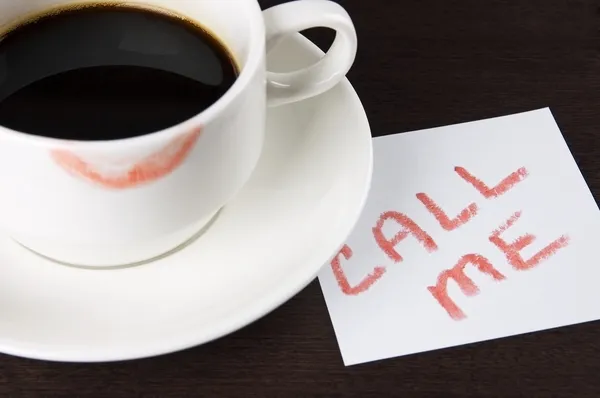 Tazza di caffè con il segno del rossetto e nota 'Chiamami' sul tavolo — Foto Stock