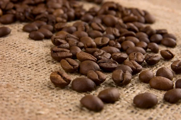 Kaffebönor på säckväv på nära håll — Stockfoto