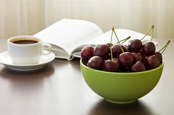 Сладкие вишни, чашка кофе и книга — стоковое фото