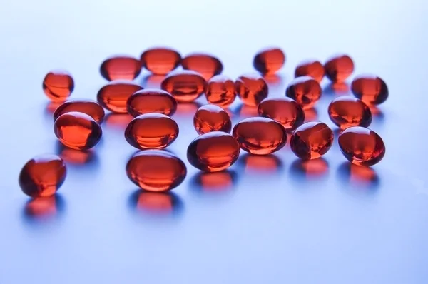 Red vitamin pills in blue light — Stock Photo, Image
