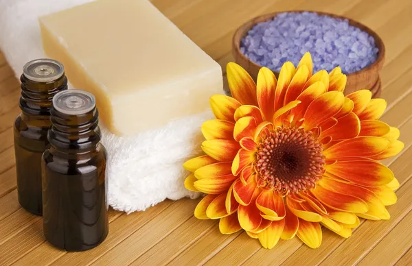 Cuidado do corpo natural, produtos de SPA: sabão orgânico, óleos de aroma, sal marinho de lavanda organizado com flor e toalha em bambu — Fotografia de Stock