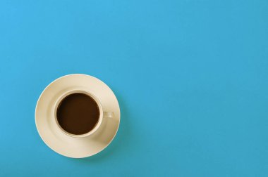 Mavi arka planda beyaz seramik fincanda sade kahve.