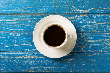 Black coffee in white ceramic cup on blue wooden table background