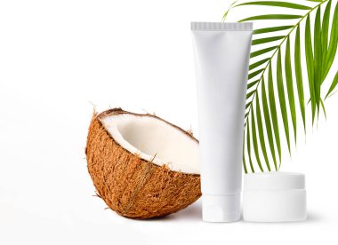 Natural coconut cosmetic concept,blank cosmetic packaging for brand name with fresh half coconut and green palm leave isolated on white background.Mock up for promote brand