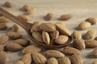 Badem tohumlarını ahşap kaşık içinde kapayın ve tahta masa arkasına badem tohumları dökülsün.